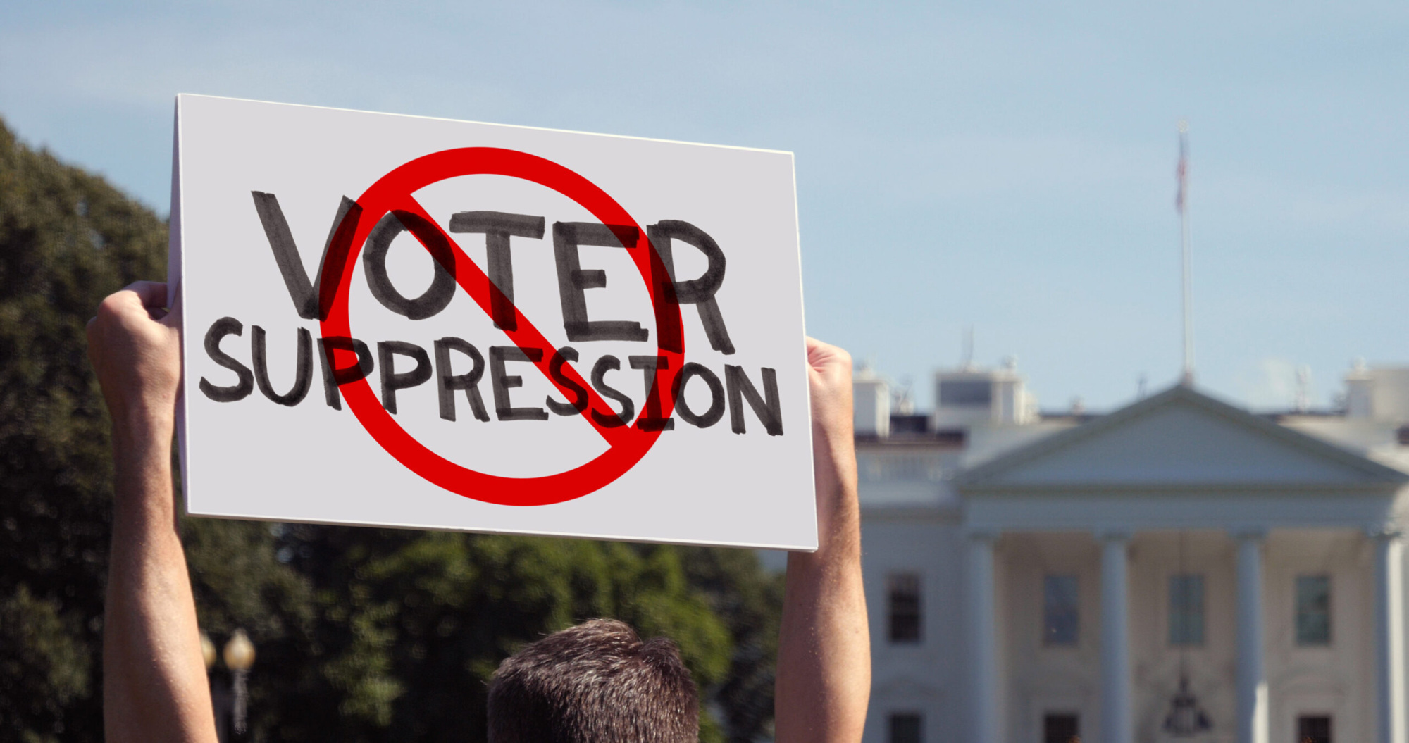 A man waves a handmade STOP VOTER SUPPRESSION protest sign outside the White House.