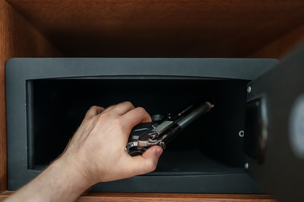 Placing a gun in a gun safe.