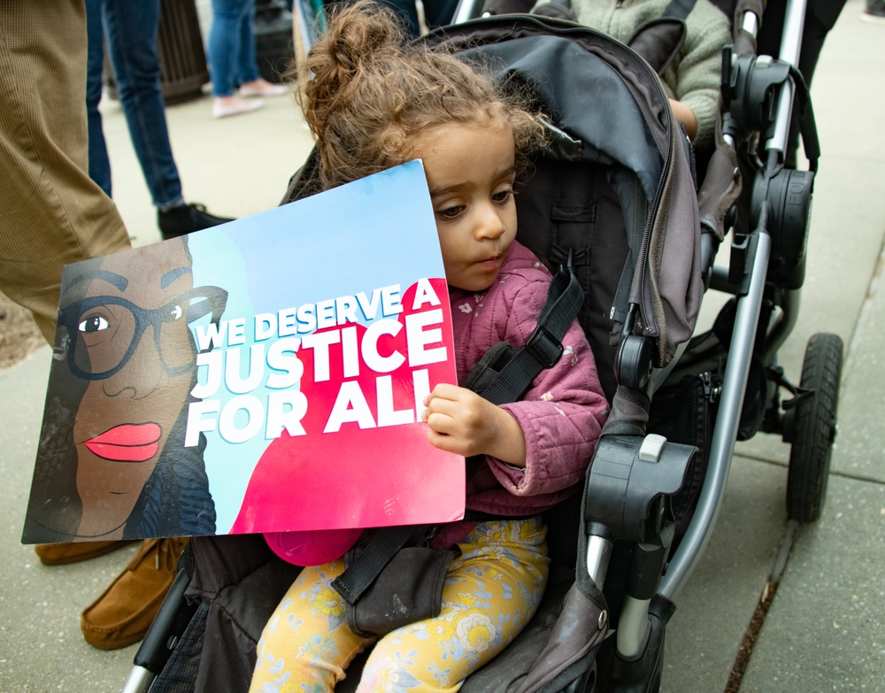 A young girl in a stroller celebrating the nomination of Ketanji Brown Jackson to the Supreme Court.